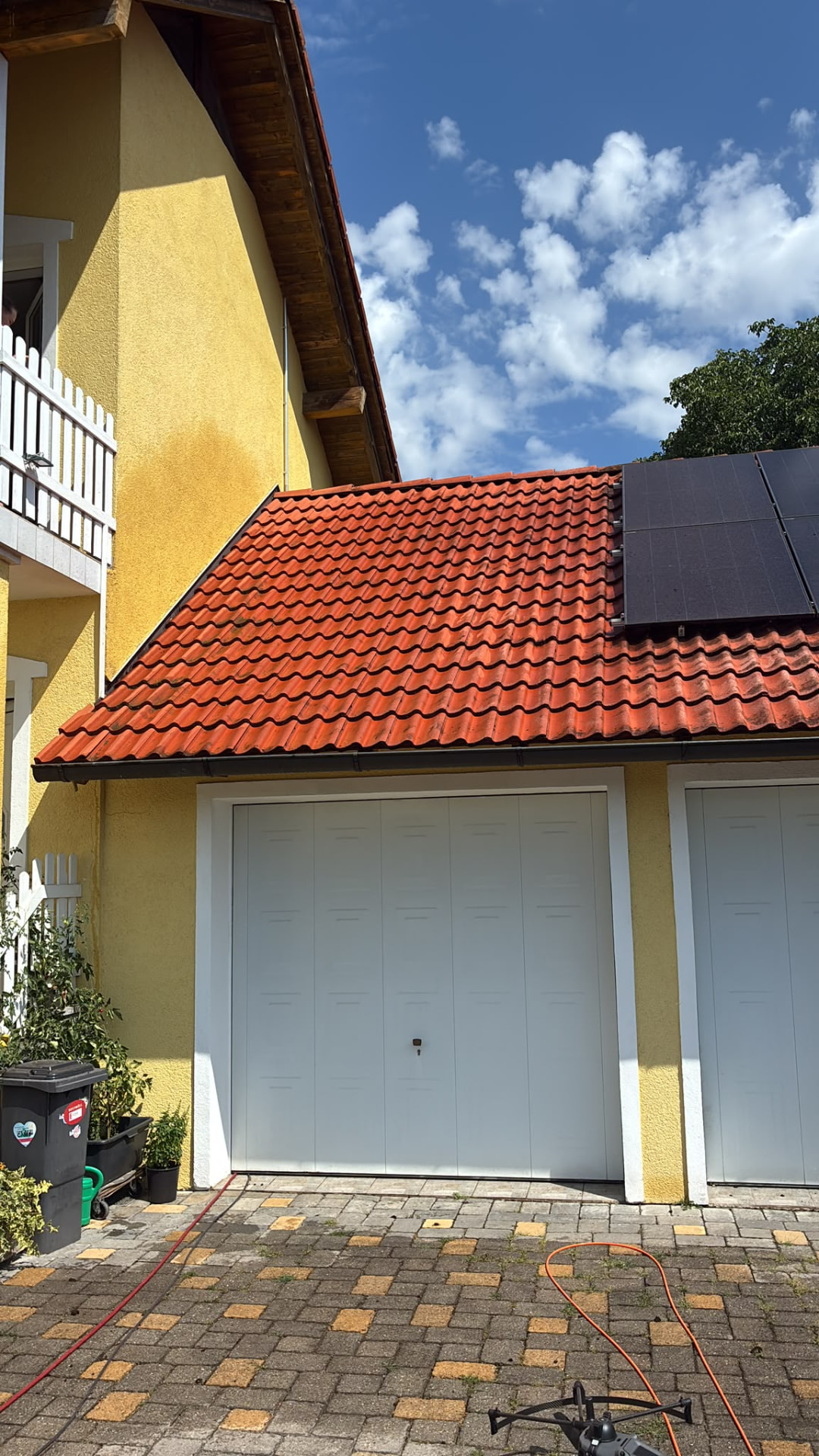 Gereinigtes Ziegeldach eines Garagenanbaus mit angrenzender PV-Anlage nach der Drohnenreinigung