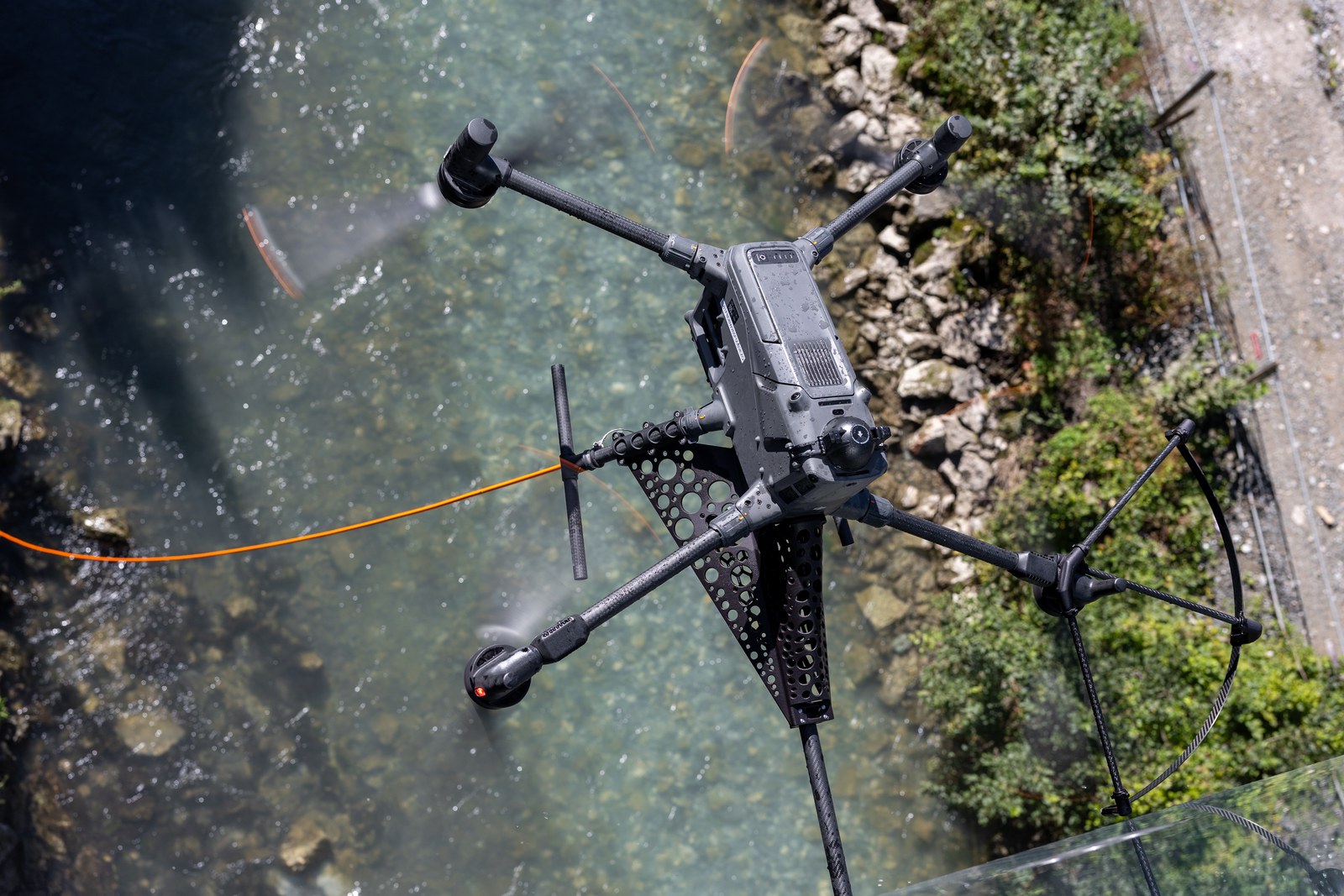 Reinigungsdrohne mit Sprühlanze von oben über dem Fluss beim Glasbrücken-Test